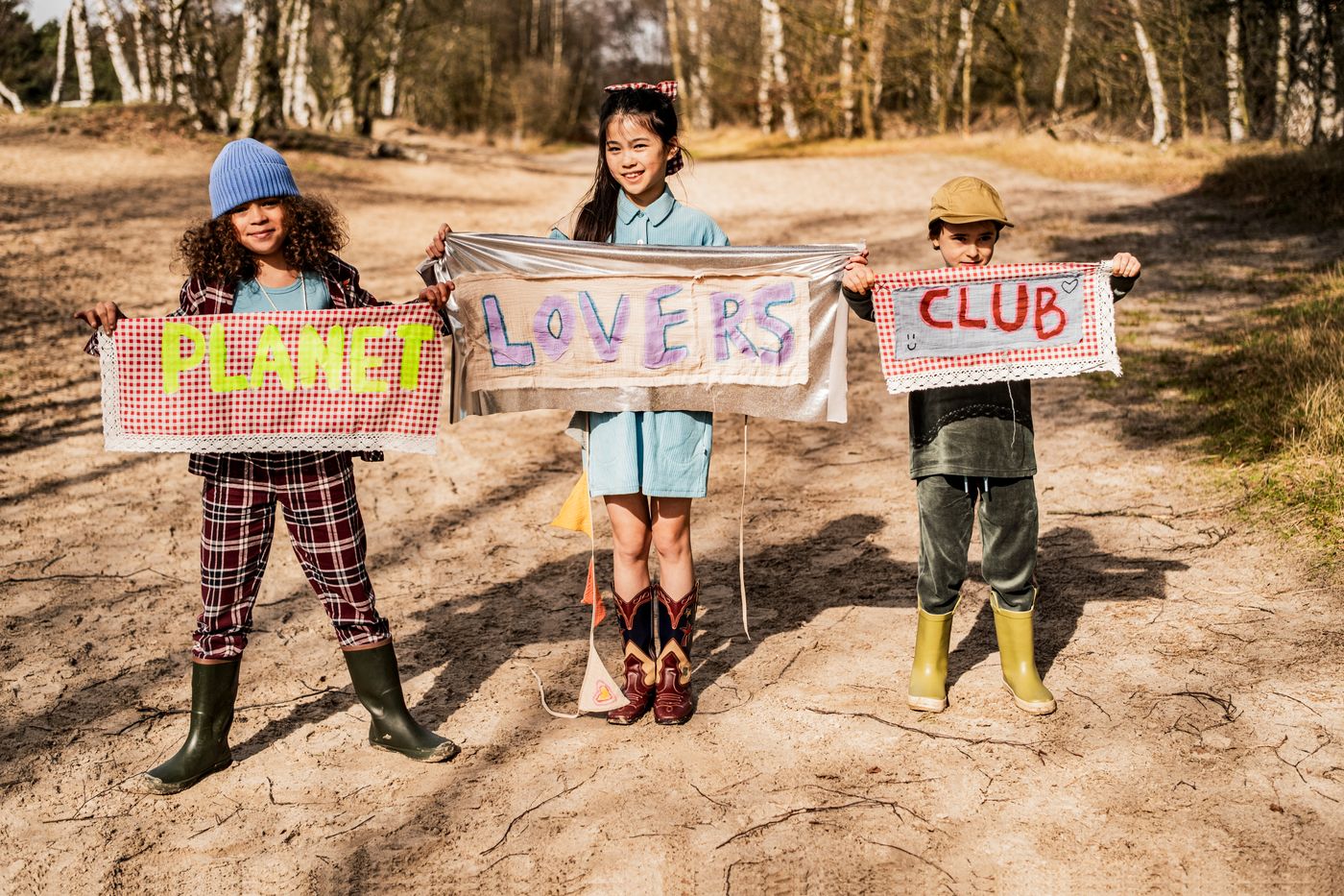Planet Lovers Club pankartı tutan üç çocuk